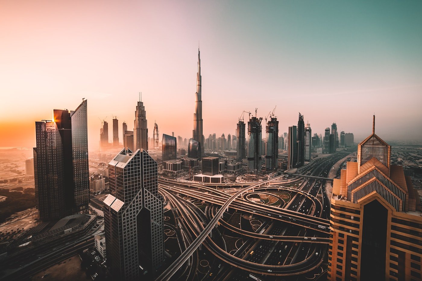 Dubai skyline at sunset with Burj Khalifa above a multi-lane highway interchange