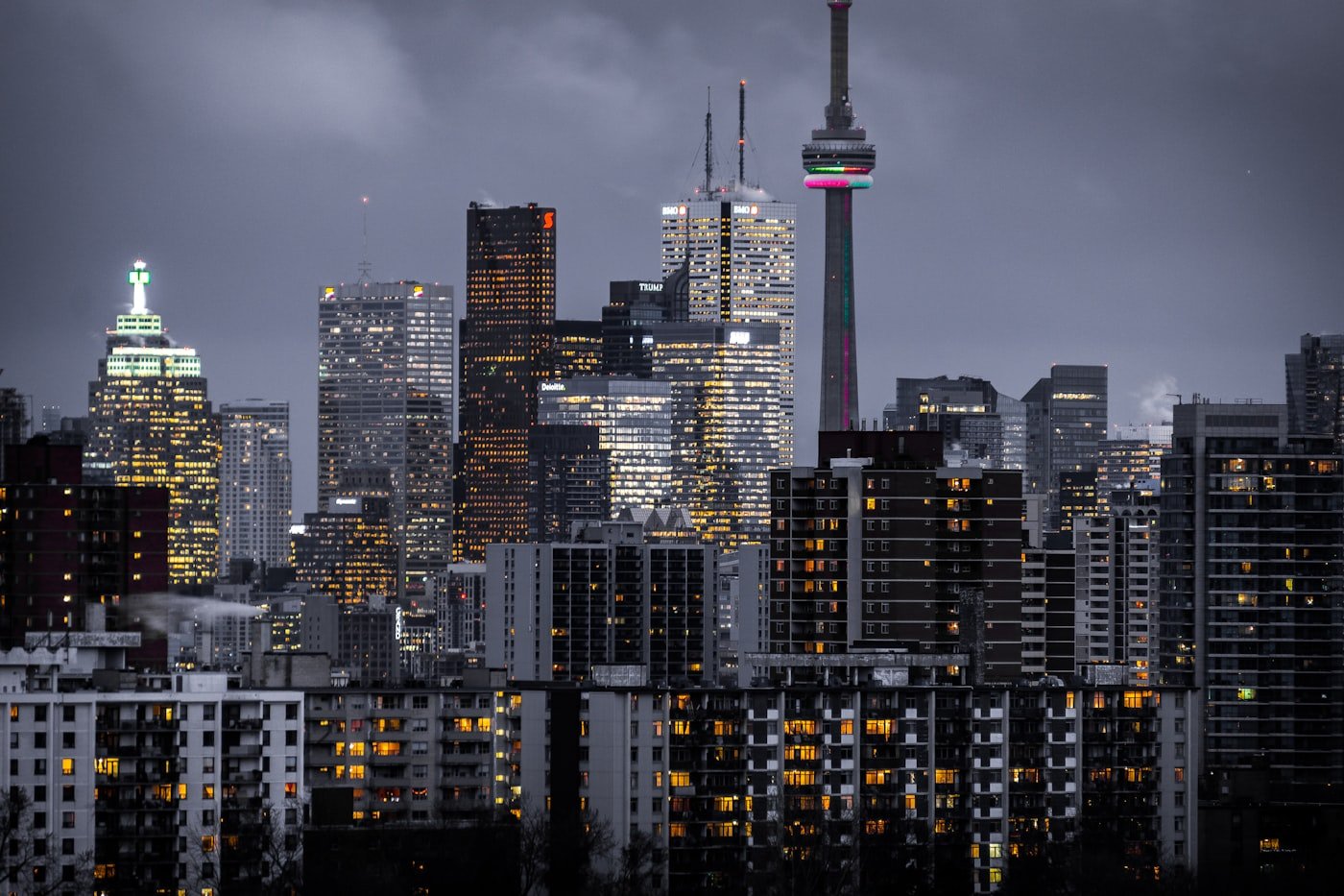 City skyline at dusk with a slender communications tower and lit high-rises