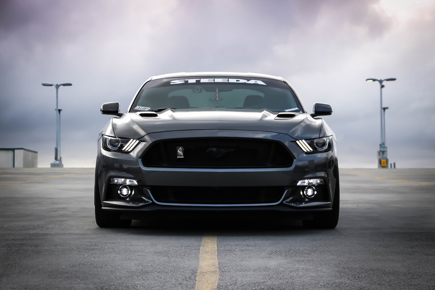 Dark sports car parked facing the camera on a paved lot