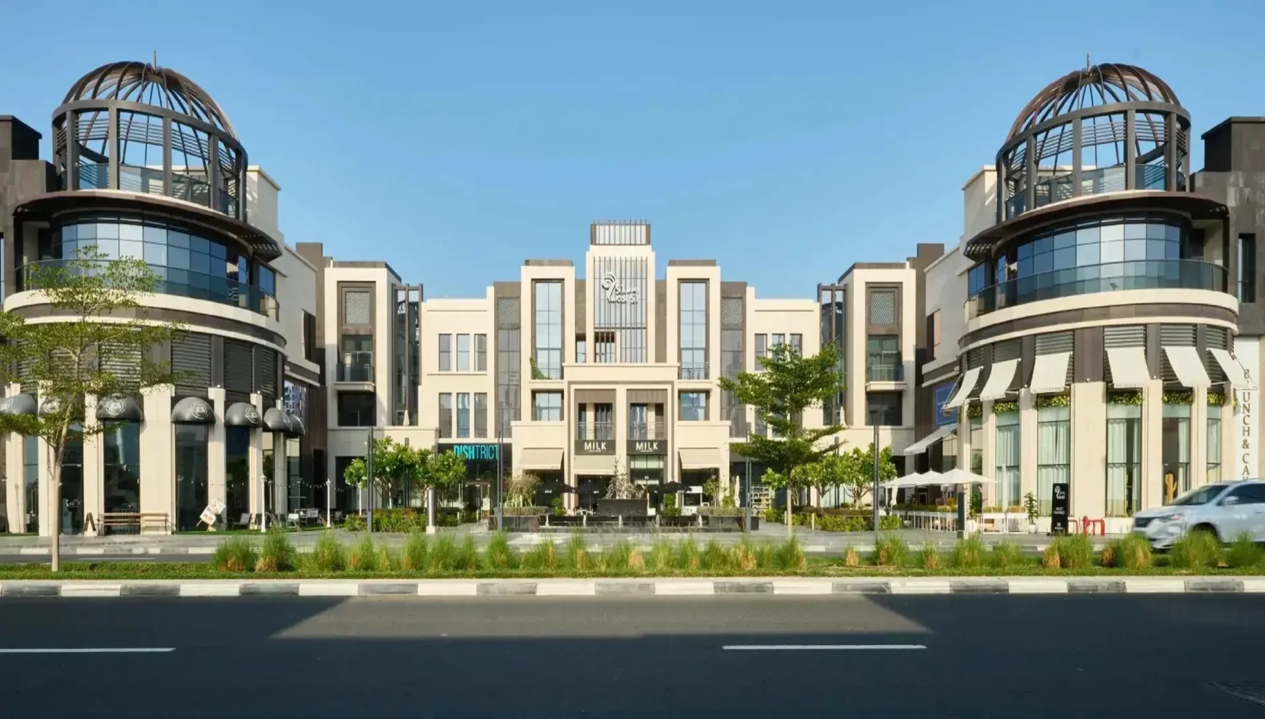 Retail and apartment frontage with two domed corner towers beside a road