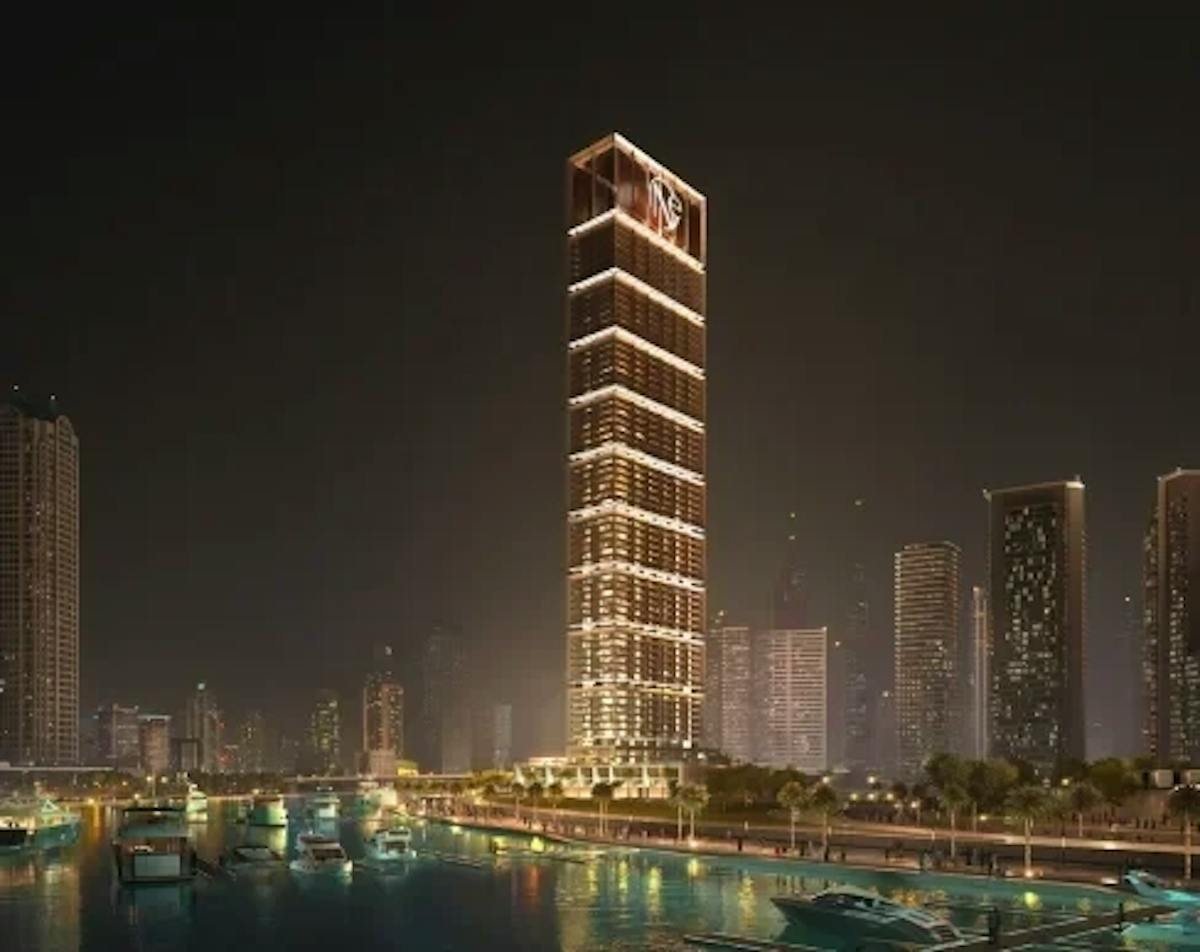 Slim residential tower lit at night beside a marina with moored boats, rendered view