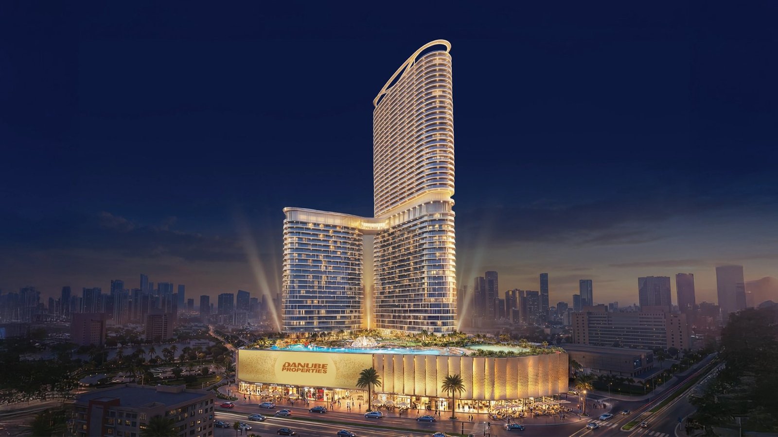 Two linked residential towers and a lit podium with a pool at night above a low-rise district, rendered view