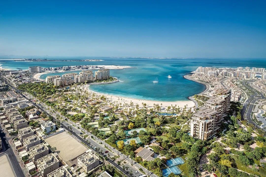 Aerial view of a beachfront community with a sandy cove and low-rise buildings, Dubai